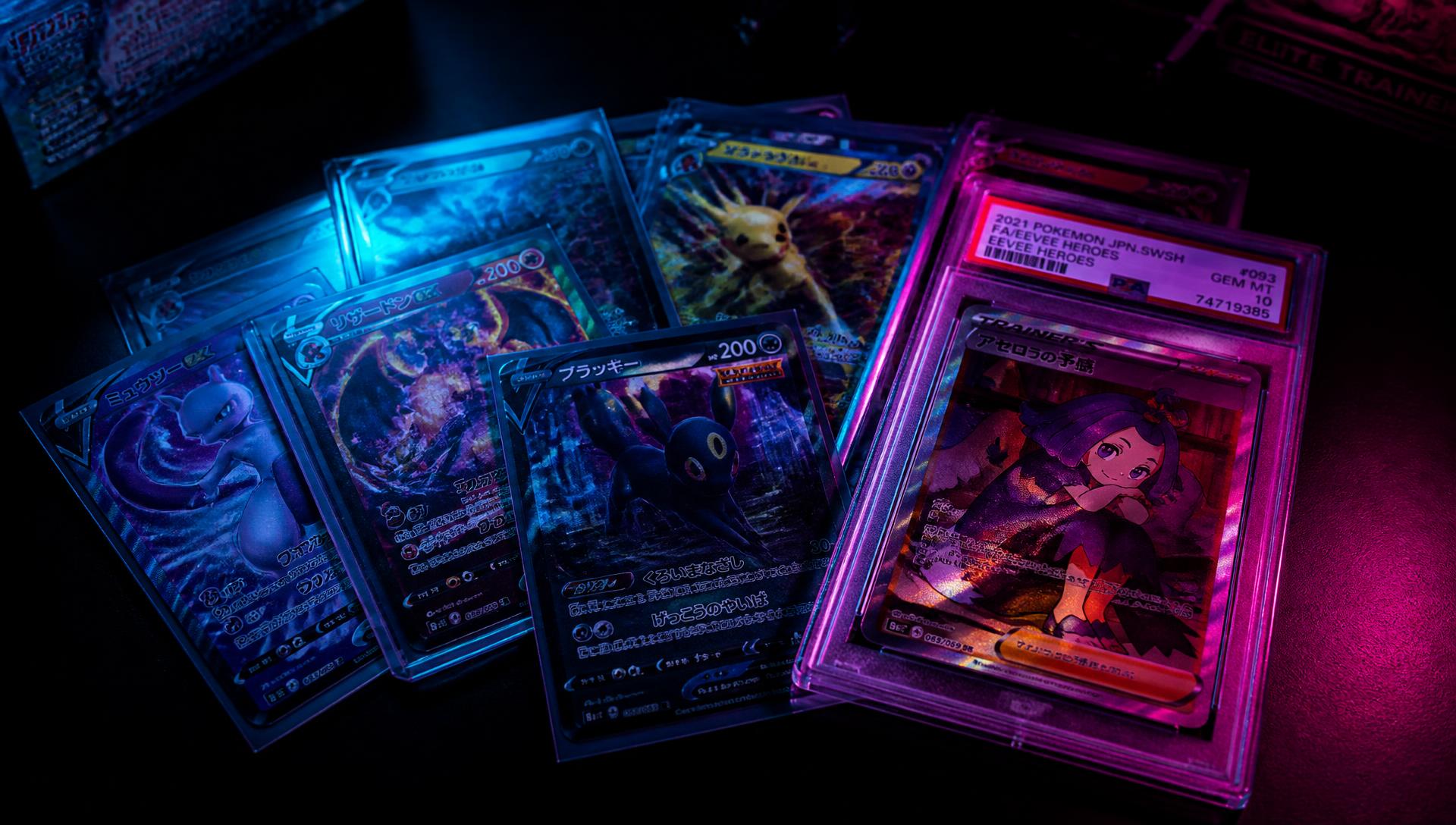 Holographic Pokémon and graded trading cards fanned out under neon lighting